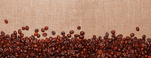 Panoramic snapshot of coffee beans on the background of sack cloth