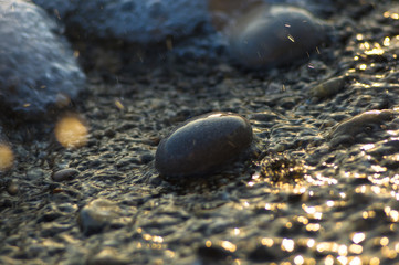 pebble stones on the sea beach, the rolling waves of the sea with foam