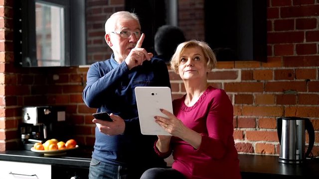 Mature couple with tablet computer standing in the kitchen
