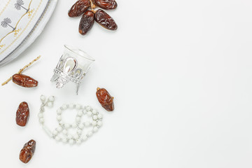 Table top view aerial image of decoration Ramadan Kareem holiday background.Flat lay date with rosary & lighting.The hat on modern rustic white wooden at office desk.Negative space creative design.