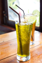 Ice lemon green tea with ice lemon tea on wooden table. Cafe view. Freshness beverage.