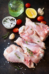 Fresh meat. Raw turkey shin, tomatoes, lemons and spices on a stone table.