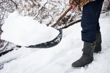 close up view of snow shovel with snow in man's hands. Man clean backyard of his house after blizzard. Spring snow cleaning.