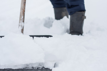close up view of snow shovel with snow in man's hands. Man clean backyard of his house after blizzard. Spring snow cleaning.