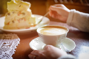 woman's hand holding cappuccino cup in the cafe