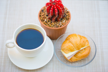 A cup of Black coffee with Ham and cheese croissant