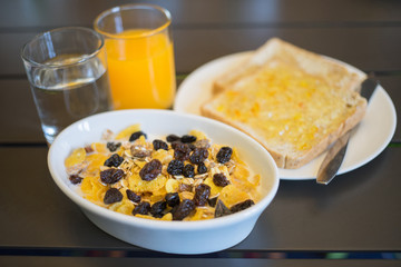 Breakfast served with water, orange juice, bread and jam, cereals milk and fruits. Balanced diet