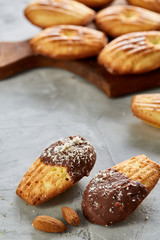 Almond cookies and raw almonds on wooden cutting board over white background, close-up, selective focus.