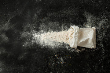 Flour sprinkled from the white paper bag on black