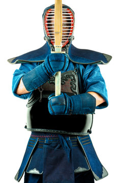 Male wearing a kendo armor with helmet and gloves holding a bamboo sword, standing position.