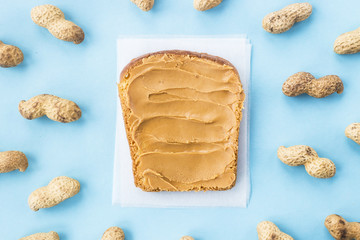 Bread toast with walnut paste among peanuts in shell and without on a blue background. Bright vegan...