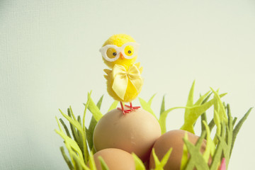 Fototapeta premium Cute Yellow chicken standing on Easter eggs among grass