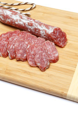 Dried sliced organic salami sausage on wooden cutting board