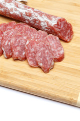 Dried sliced organic salami sausage on wooden cutting board