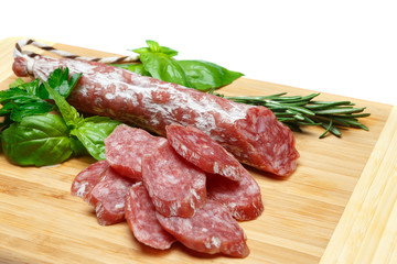 Dried sliced organic salami sausage on wooden cutting board