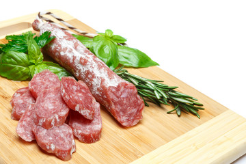 Dried sliced organic salami sausage on wooden cutting board
