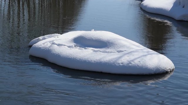 The winter river flows against the background of melting snow. Spring melting of ice.