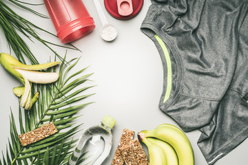 sportswear and accessories, a shaker for protein, a T-shirt with water in a bottle, bananas and cereal bars are lined with a frame, the concept of a sport lifestyle, space for text flat lay