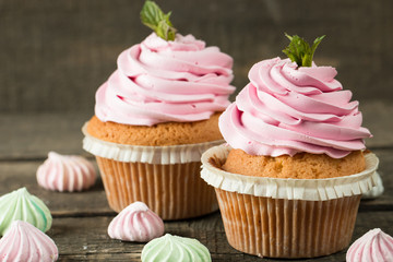 Closeup of cupcakes with vanilla, berries, pink and white cream, chocolate and sprinkles on wooden background. Selective focus. Sweet dessert tasty food concept muffin.