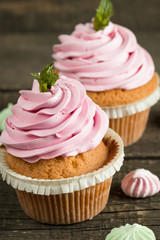 Closeup of cupcakes with vanilla, berries, pink and white cream, chocolate and sprinkles on wooden background. Selective focus. Sweet dessert tasty food concept muffin.