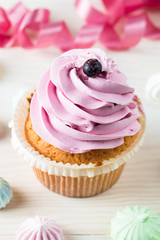 Closeup of cupcakes with vanilla, berries, pink and white cream, chocolate and sprinkles on wooden background. Selective focus. Sweet dessert tasty food concept muffin.