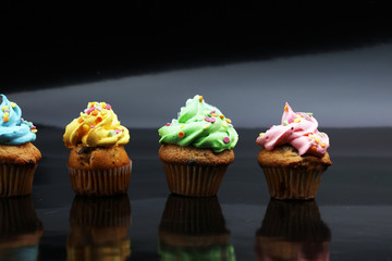 Tasty cupcakes on dark background. Birthday cupcake in rainbow colors.