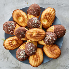 Freshly baked almond cookies piled on ceramic plate over white background, top view, close-up, selective focus