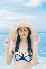 Pretty beautiful asian woman wearing colourful swimwear bikini with hat living sunbathing on the beach in the summer