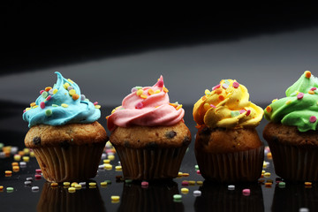 Tasty cupcakes on dark background. Birthday cupcake in rainbow colors.