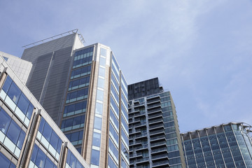 Obraz premium LONDON - MAY, 2017: Low angle view of modern glass fronted buildings against blue sky, City Of London, London