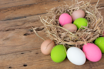 Colorful easter egg in the nest on wood background with space