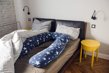 For pregnant woman sleeps comfortable U supporting pillow. Comfortable Body Pillow Pregnant Women for Side Sleepers on the bed in the interior of the bedroom © demphoto