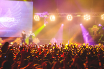 A crowded concert hall with scene stage lights, rock show performance, with people silhouette