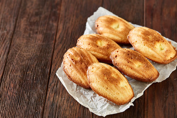 Sweet almond cookies put in rows on white paper over wooden background, close-up, selective focus