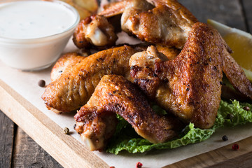 Close-up photo of bbq chicken wings with fries and beer. Barbeques meat with sauces, ketchup, mayonnaise. Fast and junk food concept. 