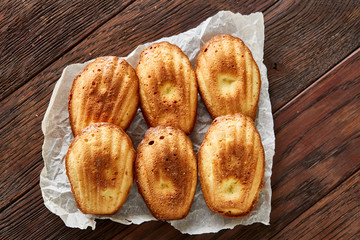 Sweet almond cookies put in rows on white paper over wooden background, close-up, selective focus