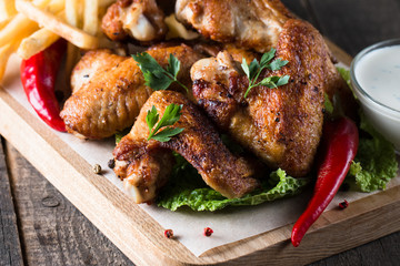 Close-up photo of bbq chicken wings with fries and beer. Barbeques meat with sauces, ketchup,...