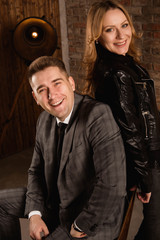 Fototapeta na wymiar Portrait of beautiful young couple in suit and leather jacket hugging and smiling.