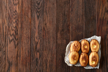 Sweet almond cookies put in rows on white paper over wooden background, close-up, selective focus