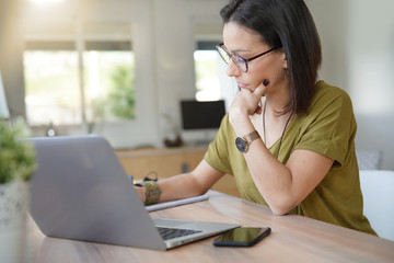 Obraz premium Woman with eyeglasses in office working on laptop
