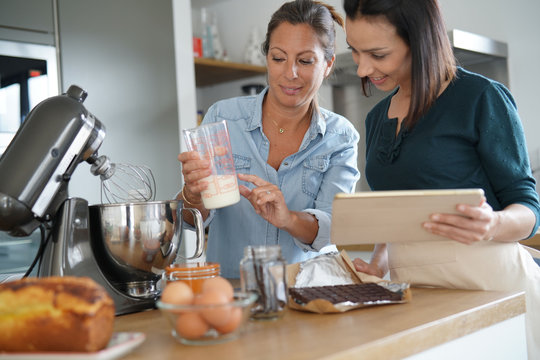 Girl friends preparing cake together with pastry robot