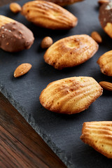 Freshly baked almond cookies on stone board over wooden background, top view, selective focus.