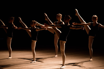 A choreographed dance of a group of graceful pretty young ballerinas practicing on stage in a...