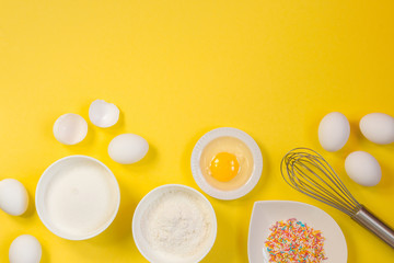 concept of the Easter bakery, various products for home baking, sugar, eggs and flour, coconut munt, top view, empty space for text on a yellow background in the style of pop art mocap layout