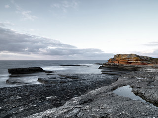 Obraz premium Seascape with bright sunset over the rocks