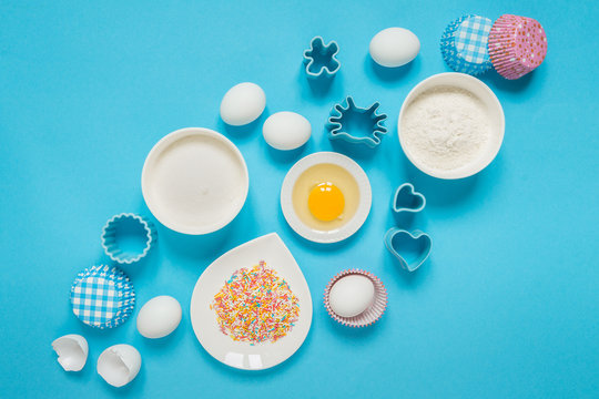 concept of the Easter bakery, various products for home baking, sugar, eggs and flour, coconut munt, top view, empty space for text on a blue background in the style of pop art mocap layout