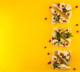 Healthy breakfast sweet toasts with apple, banana, pomegranate and caramel on yellow background. Clean eating healthy vegetarian food concept. Top view.