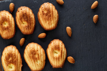 Freshly baked almond cookies on stone board over wooden background, top view, selective focus.