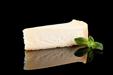 Slice vanilla cheesecake on black background.