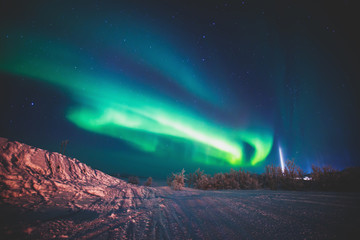 Beautiful picture of massive multicolored green vibrant Aurora Borealis, also known as Northern Lights in the night sky over winter Lapland landscape, Norway, Scandinavia
